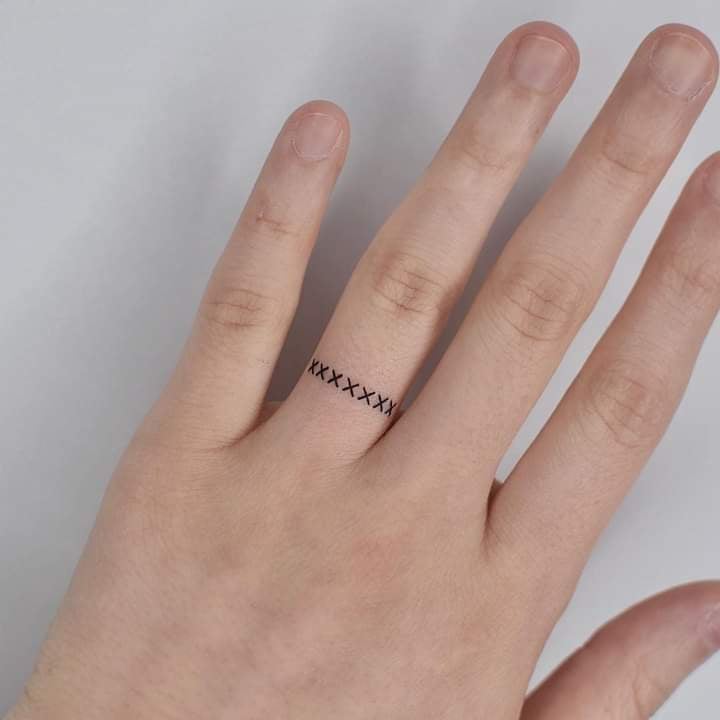 Tattoo an den Fingern der Hände kreuzt sich in Form eines Rings am Ringfinger