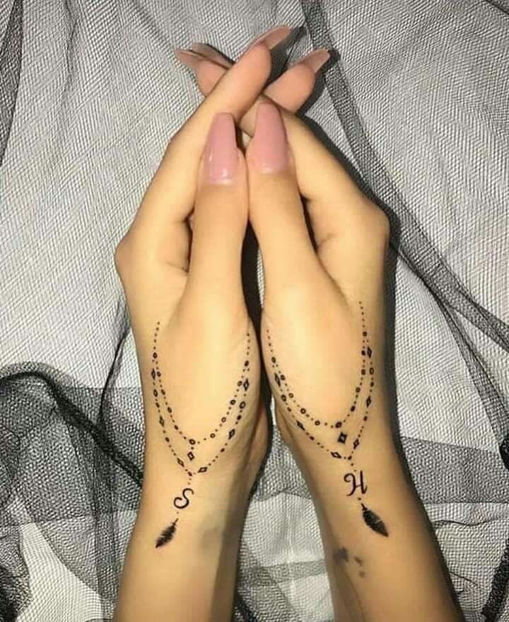 Tatuajes Bellos Mujer en dos dedos pulgares y muneca rosario inicial y pluma S H