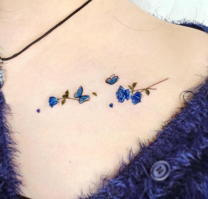 Schöne Tattoos für Frauen. Zarte blaue Blumen und Schmetterlinge auf dem Schlüsselbein