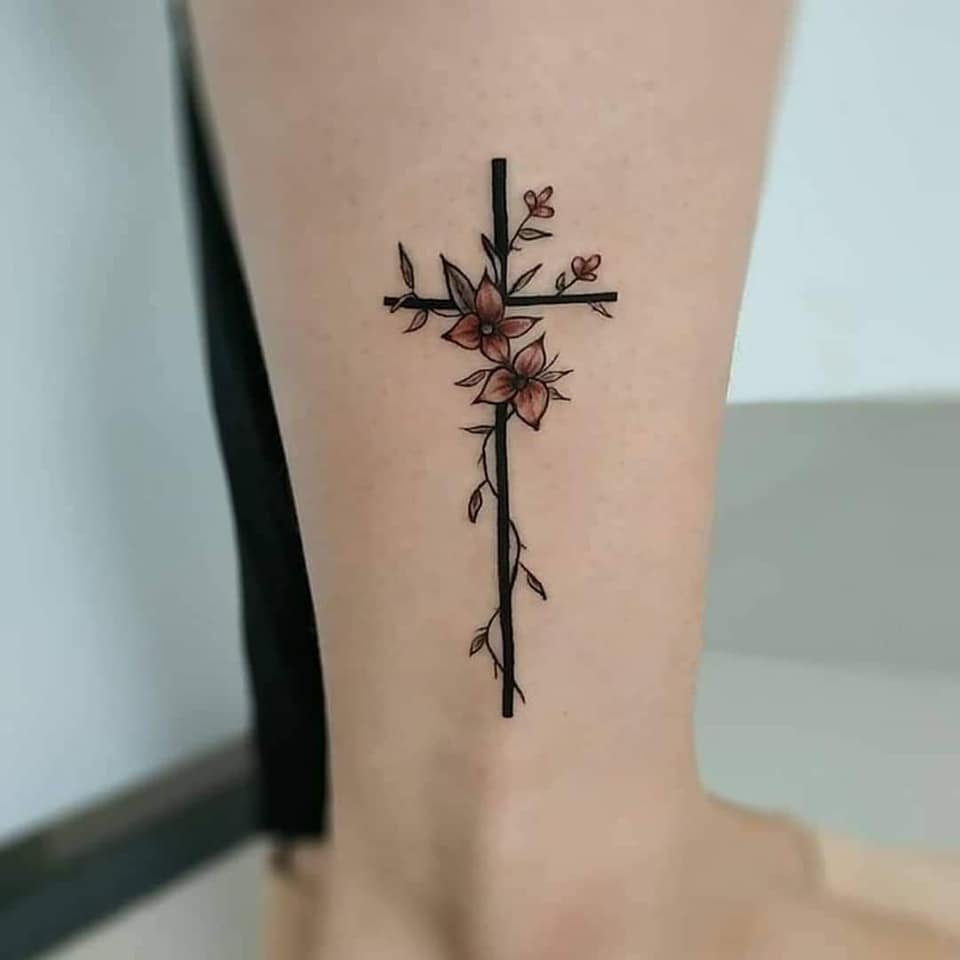 Tatuajes Bellos para Mujeres Cruz negra y detalles de flores marrones en pantorrilla