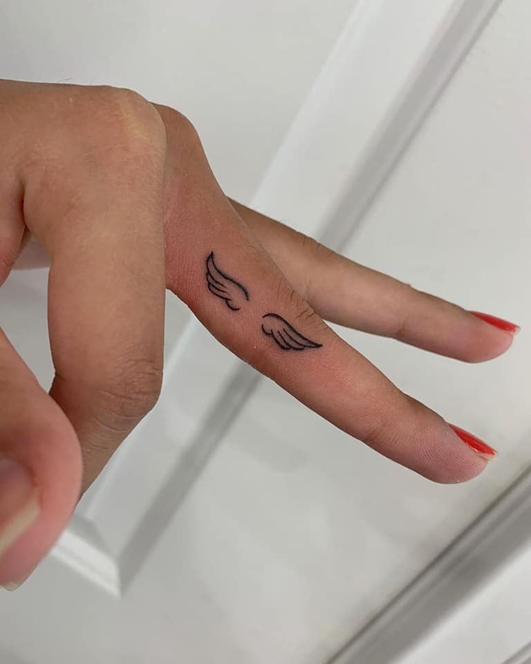 Pequenas tatuagens de asas de anjo nos dedos