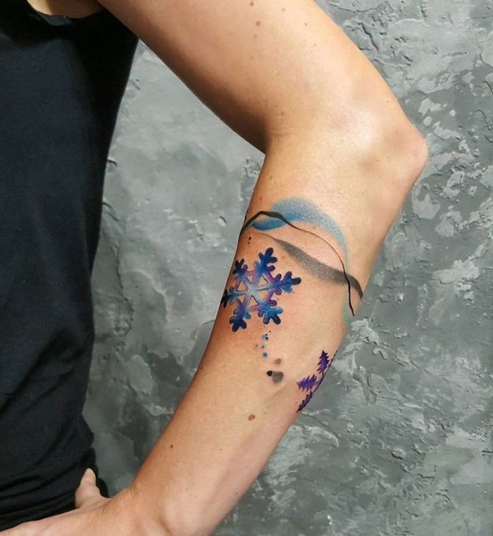 Christmas snowflake tattoos on blue woman arm