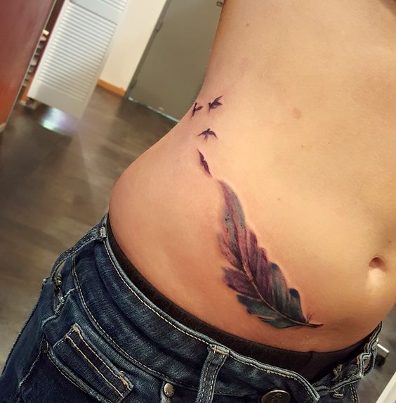 Tatuaggi di piume e uccelli sulle donne sul lato dell'addome 1