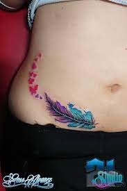 Tatuaggi di piume e uccelli sulle donne sul lato dell'addome con farfalle rosse