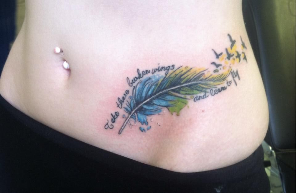 Tatuajes Pluma y Pajaros en Mujeres en bajo abdomen con frase