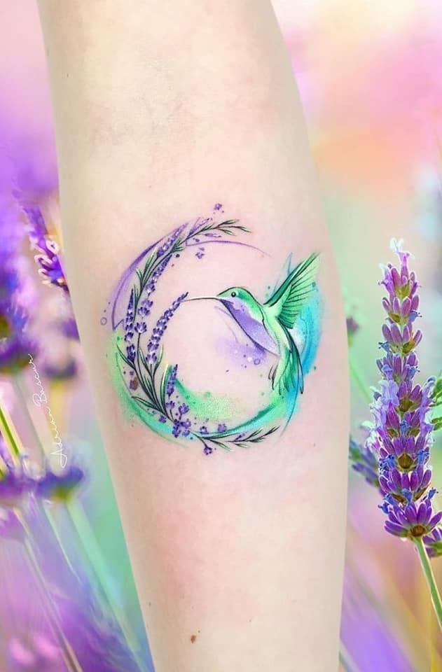 Tatuajes Realmente Bellos Mujeres colibri color lavanda con flores de lavanda y verde en antebrazo inscripto en una especie de circulo