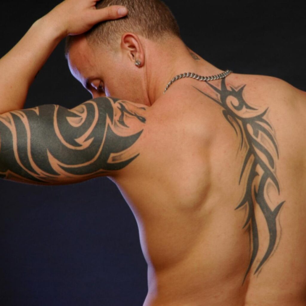 Tatuaggi tribali lungo la colonna vertebrale e sul braccio dell'uomo