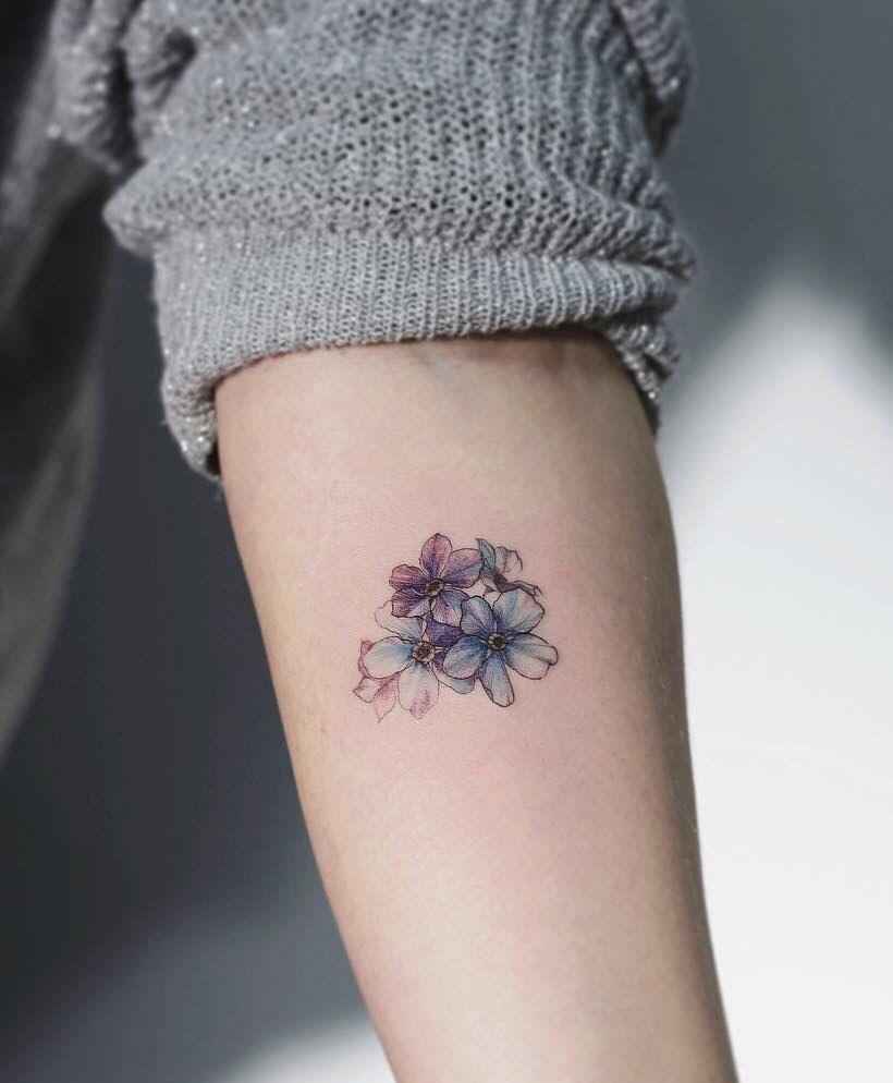 Tatuajes aesthetic super minimalistas flores delicadas y violetas y azules en brazo