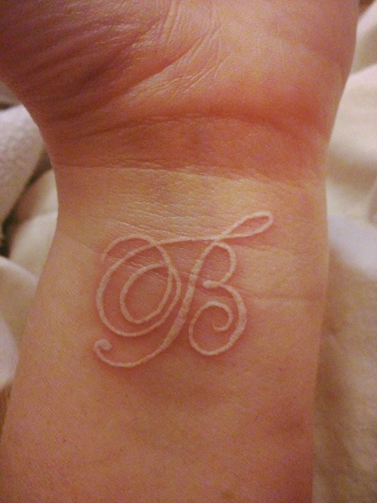 Tattoos mit den Buchstaben B in weißer Tinte am Handgelenk
