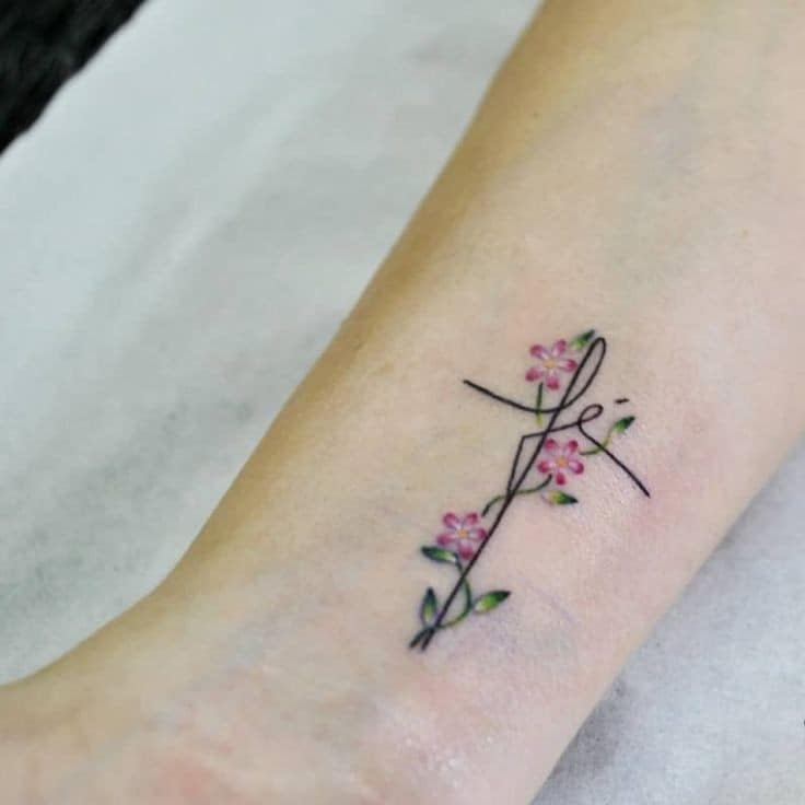 Tattoos with the word Faith small and delicate in the shape of a cross with flowers and branches
