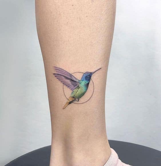 Tätowierungen einer Kolibris-Frau in Blau, Grün und Violett in einem Kreis eingraviert