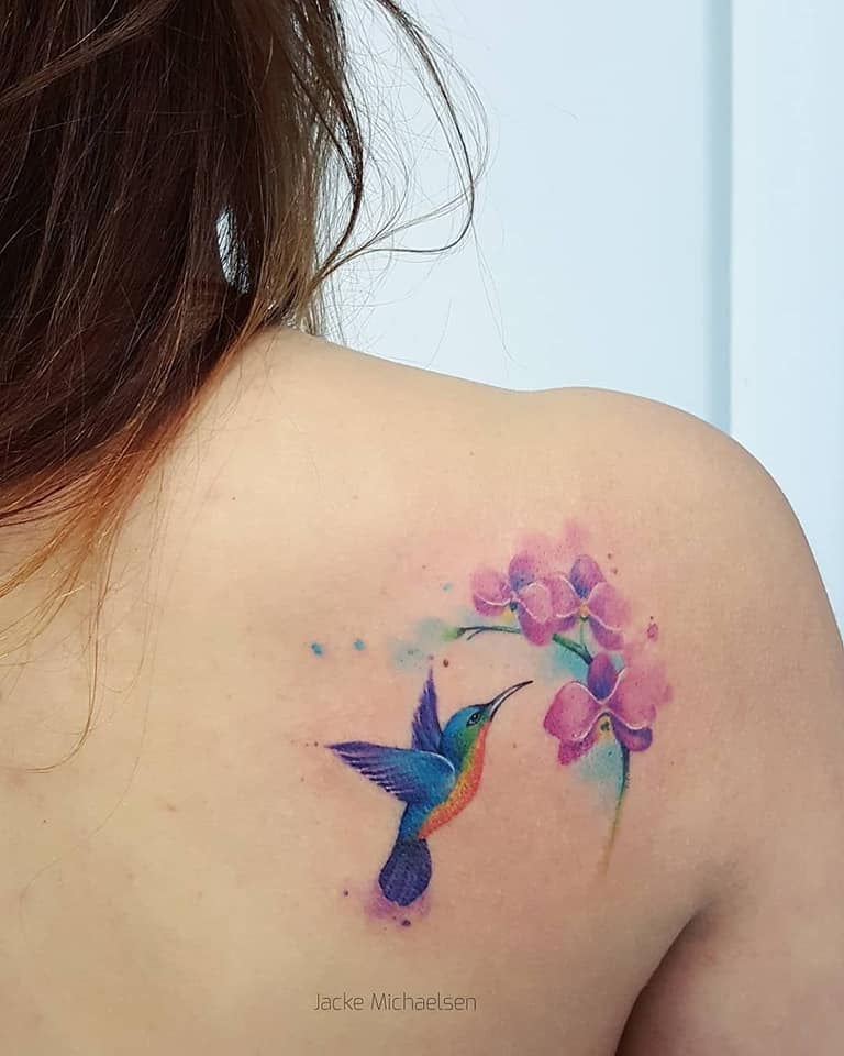 Kolibri-Tattoos Blaue und lila Frau, die eine Rosenblüte pickt