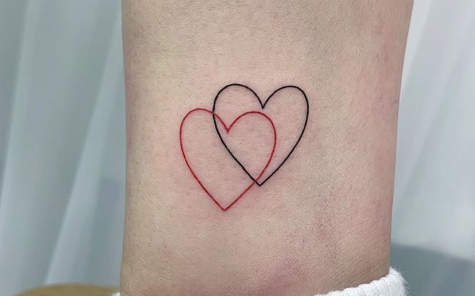 Rote und schwarze Herz-Tattoos mit feiner Linie auf der Wade