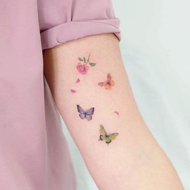 Delicati tatuaggi a farfalla Tre farfalle e una bellissima rosa con petali sul braccio