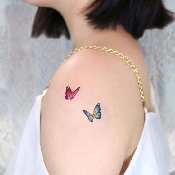 Delicati tatuaggi di farfalle, due farfalle, una rossa e una azzurra, sulla spalla