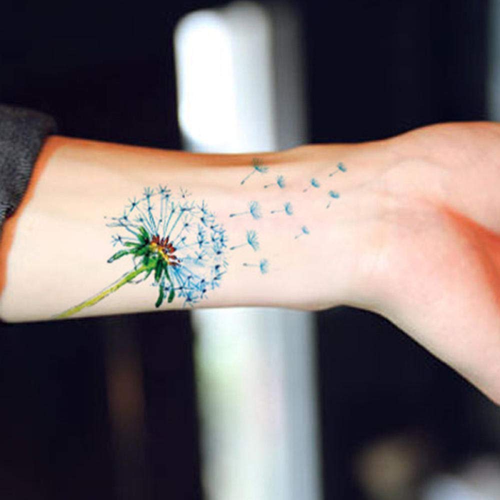 Dandelion tattoos on light blue wrist with flying seeds