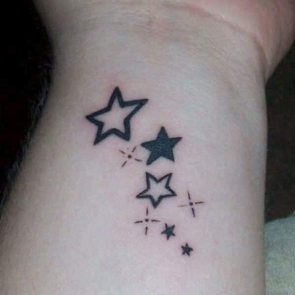 Star tattoos, some filled, others not on the wrist