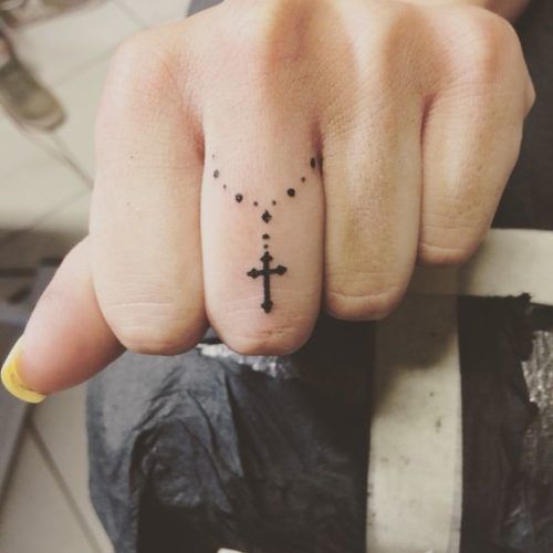 Tatuajes de Fe y Cruces Mujer rosario y cruz en dedo