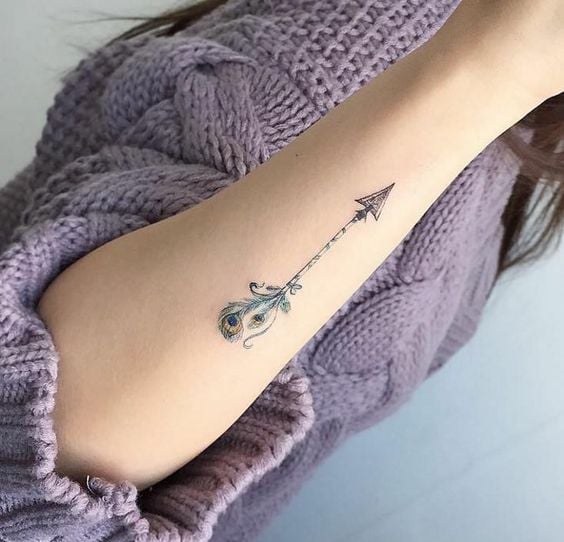 Tatuagens delicadas de flechas no antebraço de mulher com pena 77