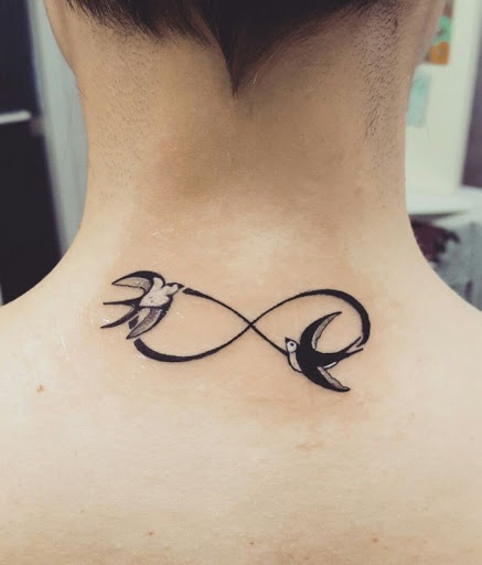 Tatuaggi infinito con due rondini su entrambi i lati del nastro sotto il collo sulla schiena