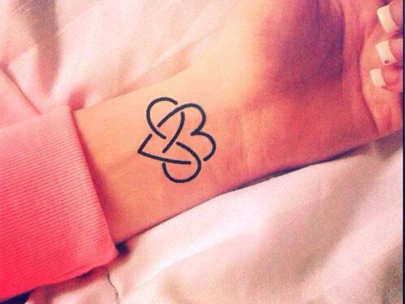 Tatuagens de infinito entrelaçadas com tatuagem de coração no pulso