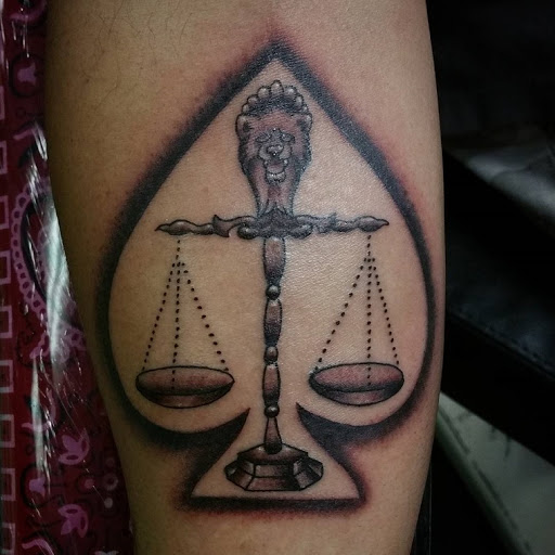 I tatuaggi della Bilancia sono inscritti nel simbolo di una bilancia della giustizia a forma di picca con un pugnale di leone