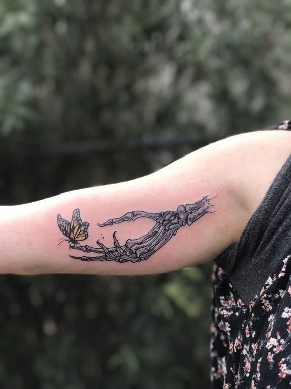 Main squelette avec des tatouages de papillon sur le bras des femmes