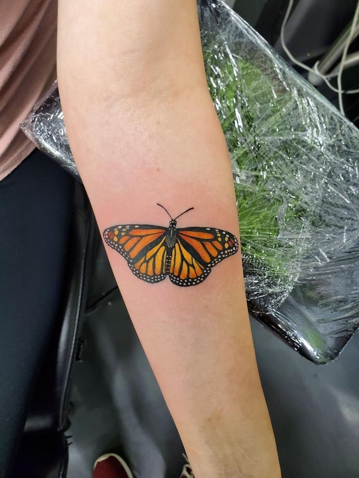 Orangefarbene Schmetterlings-Tattoos auf dem Unterarm 1