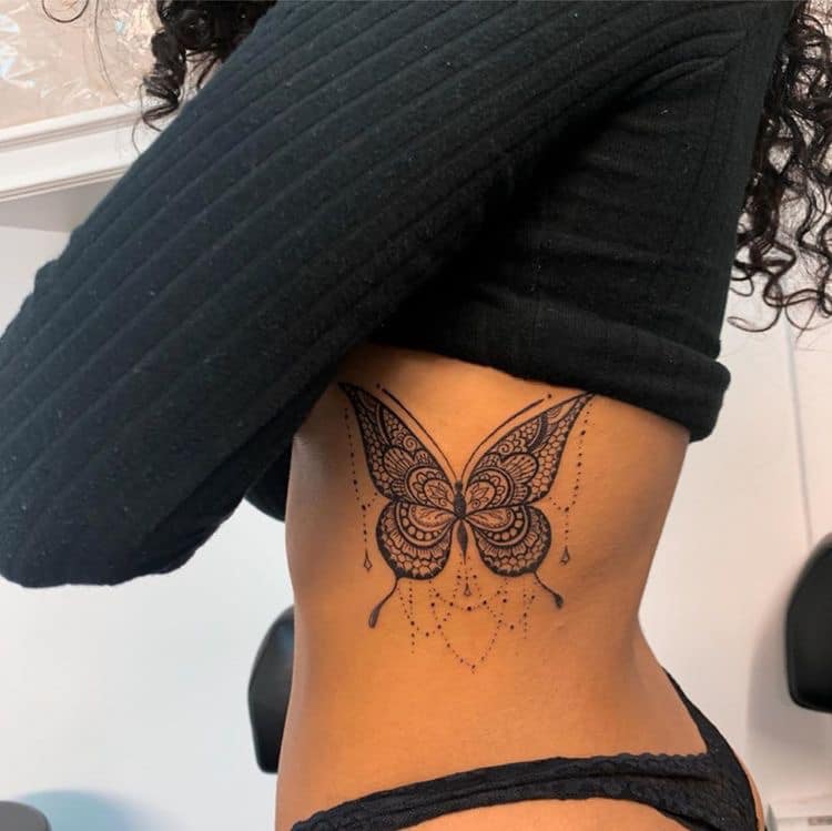 Tatouages de papillons noirs sur les côtes avec des décorations d'attrape-rêves