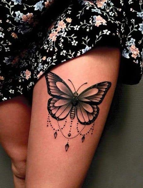 Tatuagens de mariposas borboletas negras na coxa com correntes e pingentes