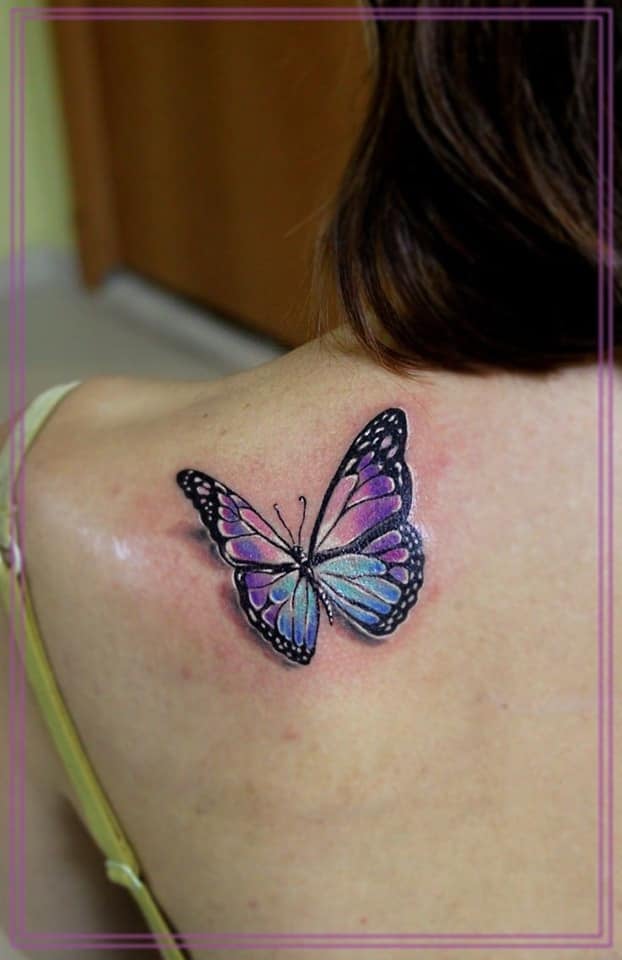 Papillon tatoue un papillon violet et bleu clair sur l'épaule
