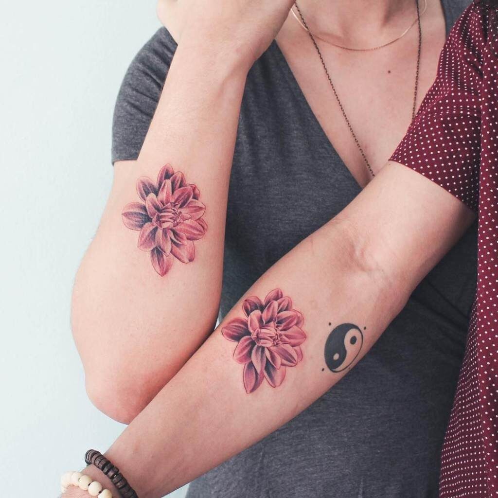 Passende Tattoos für Freunde, Paare, Schwestern. Zwei rote Blumen auf beiden Unterarmen plus Yin-Yang