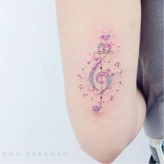 Tatuagens de música de clave de sol violeta e rosa no cotovelo