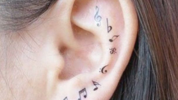 Musik-Tattoos im Ohr: Violinschlüssel und verschiedene Musiknoten