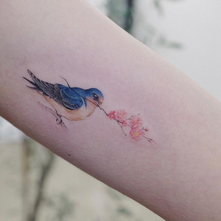 Tatuaggi di uccelli con ramo con fiori nel becco