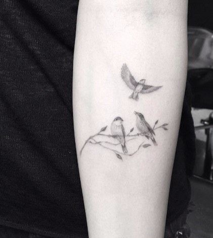 L'uccello tatua tre uccelli neri sull'avambraccio