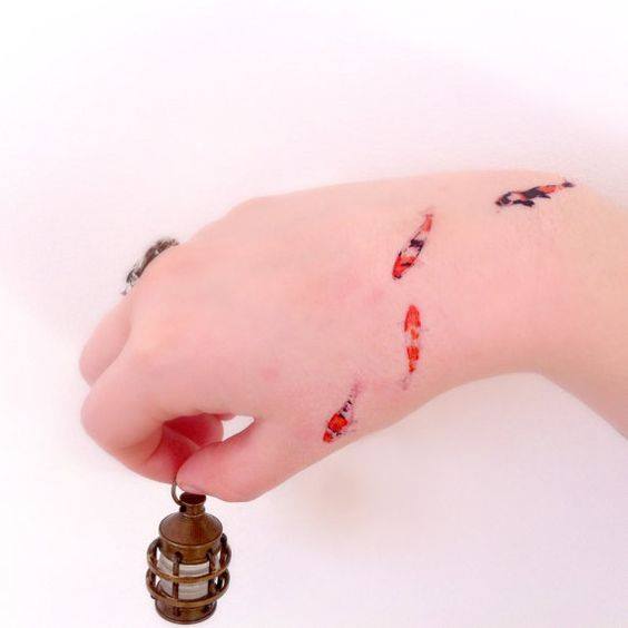 Tatuajes de Peces cuatro peces en mano