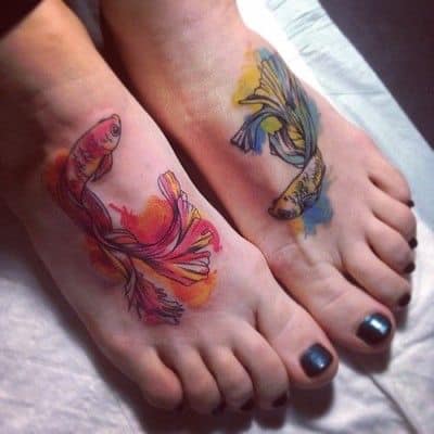 Tatuaggi di pesci arancioni, blu e gialli su entrambi i piedi