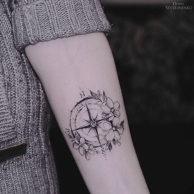Tatuajes de Rosa de los Vientos o Brujula en negro con flores en antebrazo