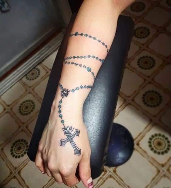 Tattoos von Rosenkränzen. Glaubensrosenkranz auf dem gesamten Unterarm und Kreuz auf der Hand