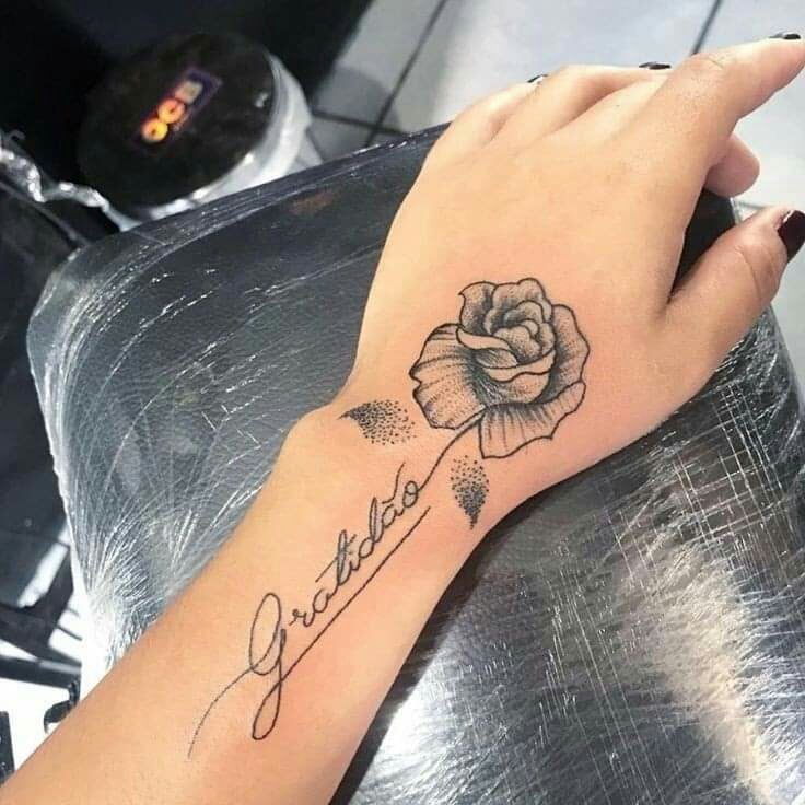 Tatouages de roses noires sur les mains avec un nom sortant vers le bras