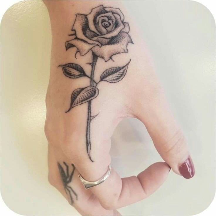 Tatuagens de rosas negras nas mãos de um lado e aranha no dedo