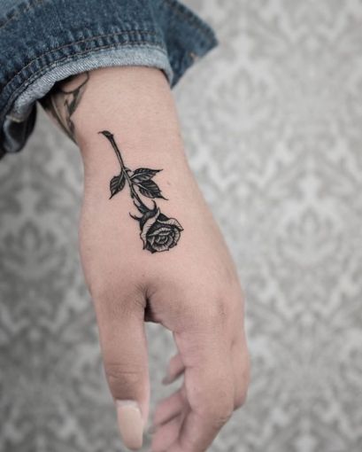 Tatuaggi di rose nere sulle mani di un ragazzo di taglia media sul lato della mano