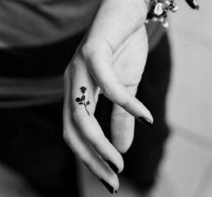 Tiny minimalist black rose tattoos on the side of the ring finger
