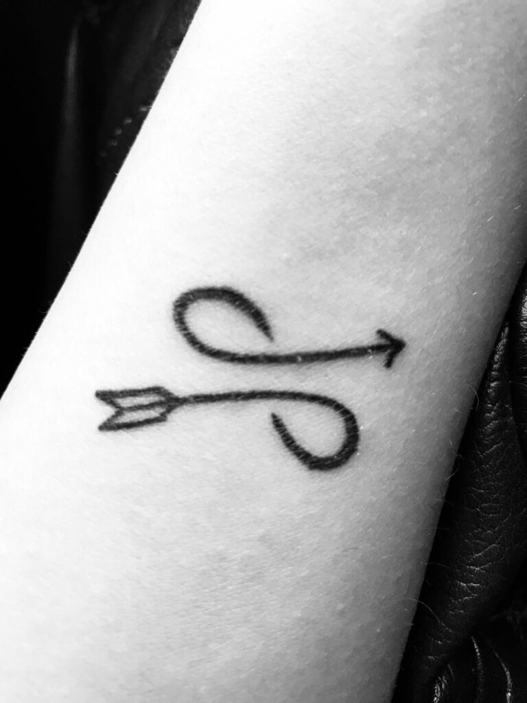 Tatuajes de Simbolo Malin infinito mas flecha en muneca