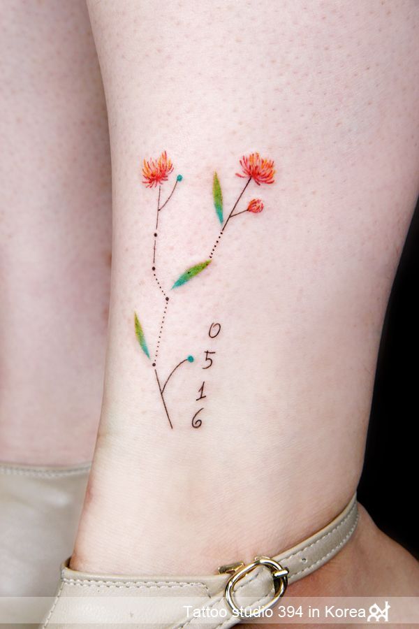 Tatouages de la constellation du Taureau faits de fleurs et de branches plus des chiffres sur le mollet