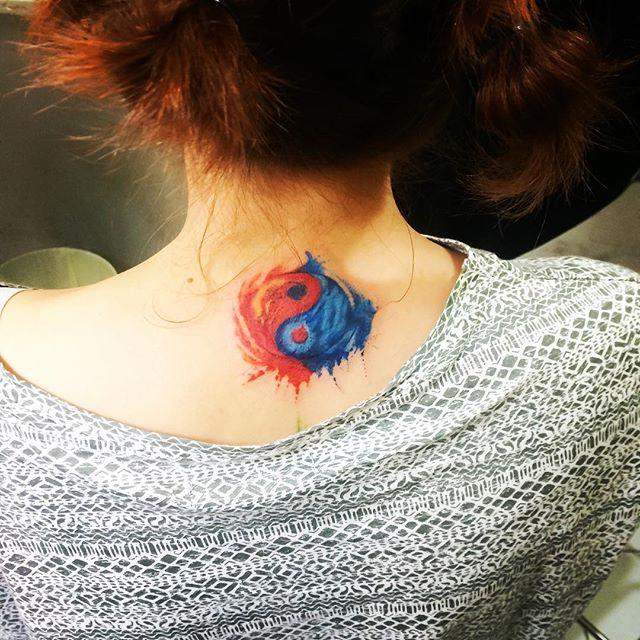 Tatuajes de Yin Yang en base de la nuca cuello en colores azul y naranja