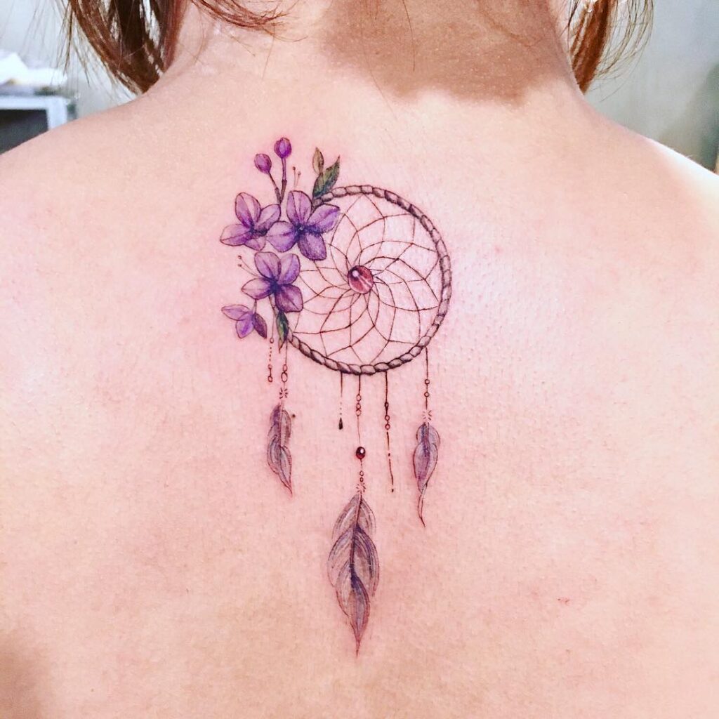 Tatuajes de atrapasuenos llamadores de angeles en espalda con flores violaceas