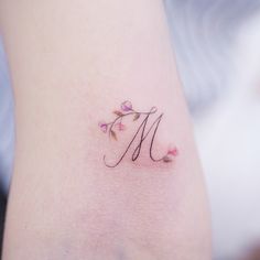 Tatuajes de la letra M eme adornada con florcitas y trazo fino