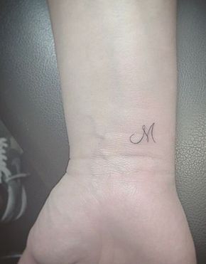 Tattoos of the letter M small on a very thin wrist